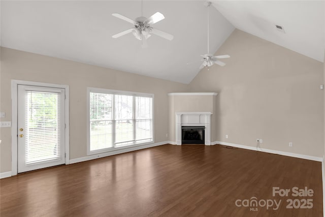 unfurnished living room with a glass covered fireplace, baseboards, dark wood-style floors, ceiling fan, and high vaulted ceiling