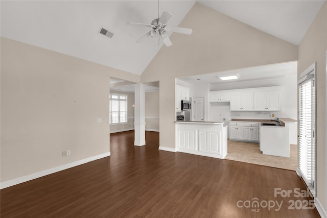 unfurnished living room with visible vents, high vaulted ceiling, wood finished floors, and a ceiling fan