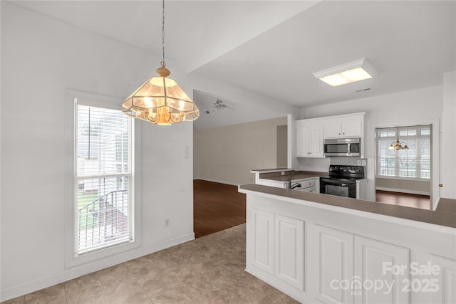 kitchen featuring hanging light fixtures, baseboards, black electric range oven, stainless steel microwave, and white cabinetry
