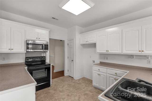 kitchen featuring white cabinets, visible vents, stainless steel microwave, and black range with electric cooktop