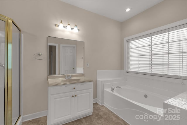 bathroom featuring a bath, vanity, baseboards, and a stall shower