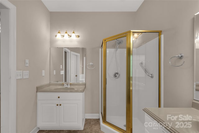 bathroom featuring vanity, baseboards, and a stall shower