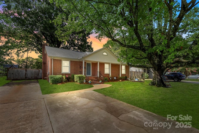 view of front of property featuring brick siding, a lawn, a chimney, and fence