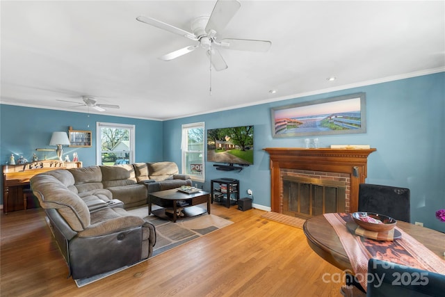 living area with ornamental molding, a fireplace, baseboards, and wood finished floors