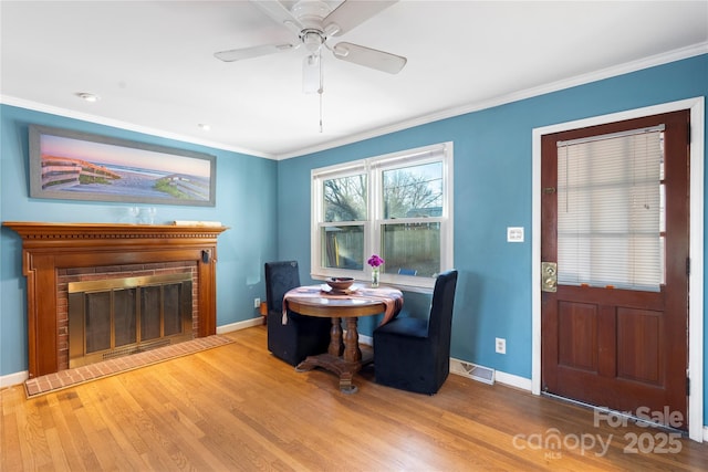 interior space featuring a brick fireplace, wood finished floors, visible vents, and crown molding