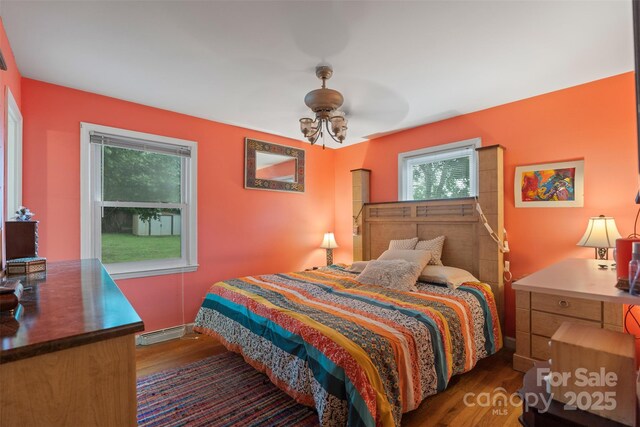 bedroom with a baseboard heating unit and wood finished floors