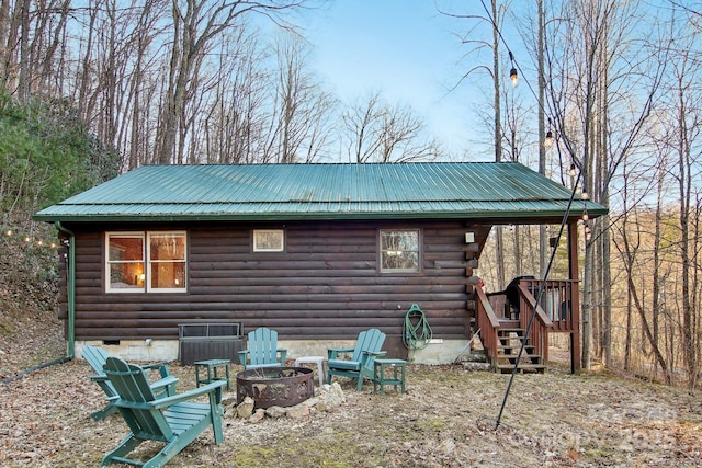 back of house with a fire pit, log exterior, crawl space, and metal roof