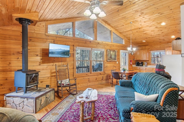 living area featuring lofted ceiling, wood walls, wood finished floors, wood ceiling, and a wood stove