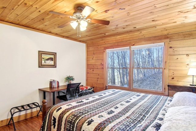 bedroom featuring wood walls, wood finished floors, a ceiling fan, wood ceiling, and baseboards