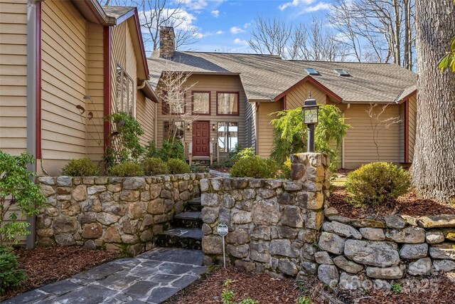 property entrance featuring roof with shingles and a chimney