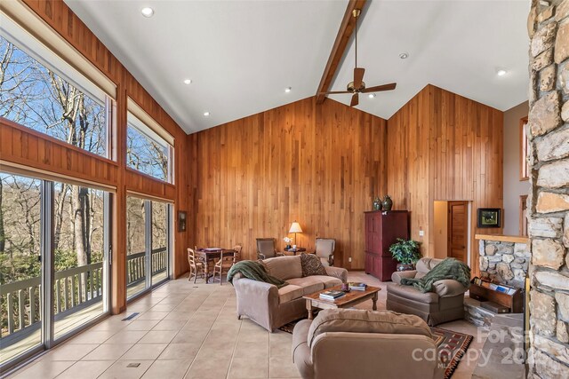 living room with light tile patterned floors, high vaulted ceiling, a ceiling fan, and wood walls