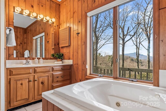 bathroom with wood walls, a tub with jets, vanity, tile patterned floors, and a mountain view