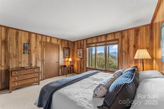 bedroom with wooden walls, crown molding, light carpet, and a textured ceiling