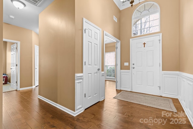 entrance foyer featuring visible vents, dark wood-style flooring, and wainscoting