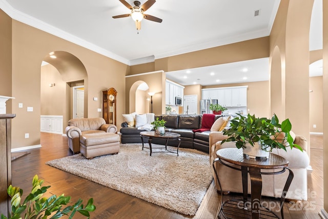 living area with hardwood / wood-style flooring, arched walkways, and ornamental molding