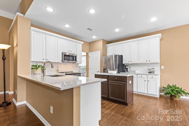 kitchen featuring dark wood-type flooring, a sink, a center island, appliances with stainless steel finishes, and decorative backsplash