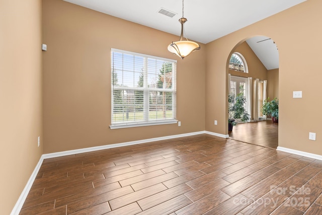 unfurnished room with arched walkways, visible vents, wood tiled floor, vaulted ceiling, and baseboards