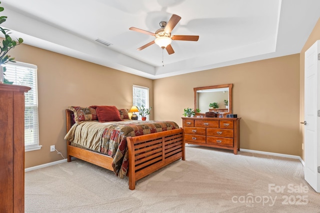 bedroom with carpet, visible vents, a raised ceiling, and baseboards