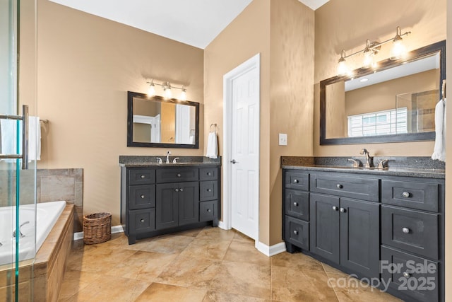 bathroom with a garden tub, baseboards, two vanities, and a sink