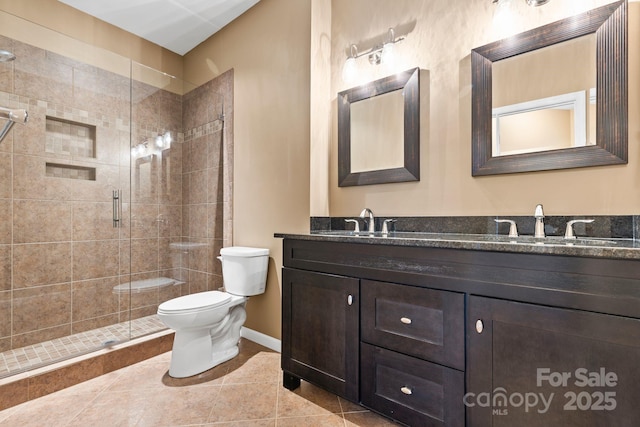 bathroom featuring double vanity, toilet, a stall shower, tile patterned flooring, and baseboards