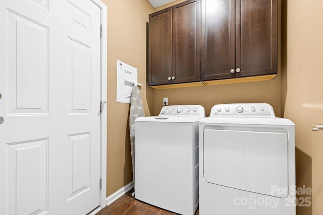 laundry area with dark wood-type flooring, washing machine and dryer, cabinet space, and baseboards