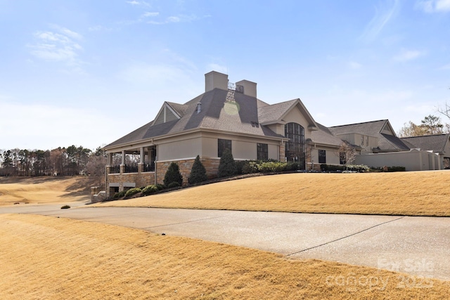 view of front of home with stone siding, a chimney, and stucco siding