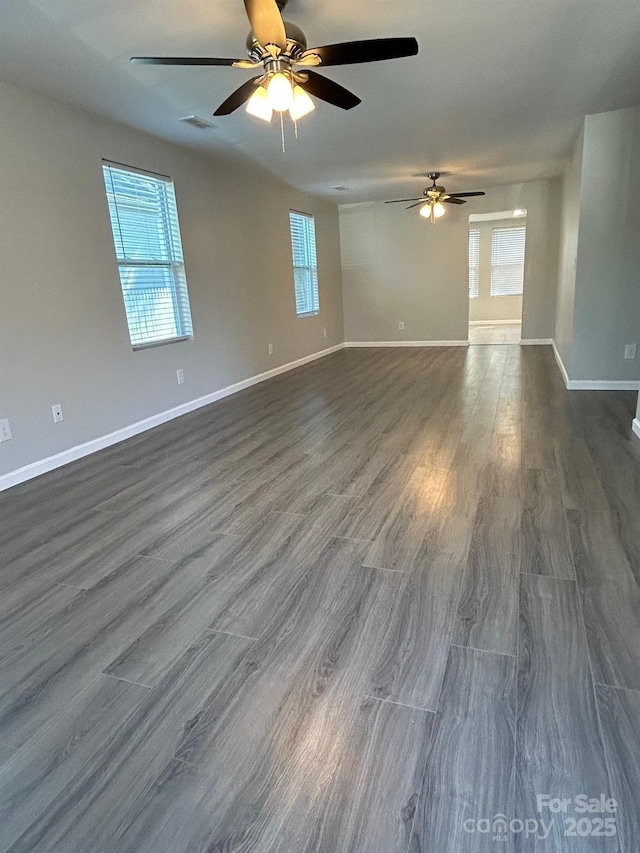 spare room with dark wood-type flooring, visible vents, baseboards, and a ceiling fan