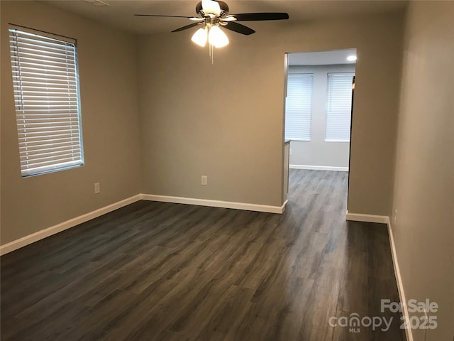 spare room with plenty of natural light, dark wood finished floors, a ceiling fan, and baseboards