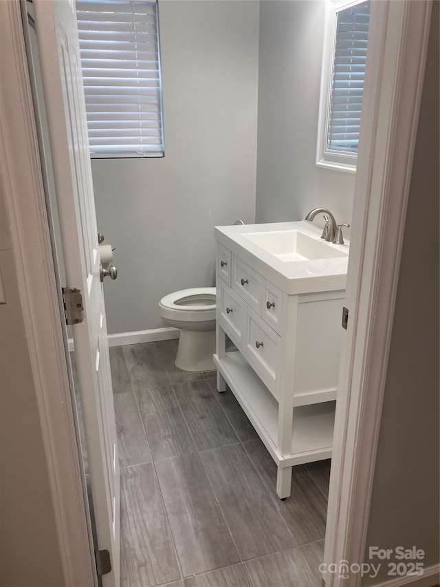 bathroom with a wealth of natural light, vanity, toilet, and baseboards