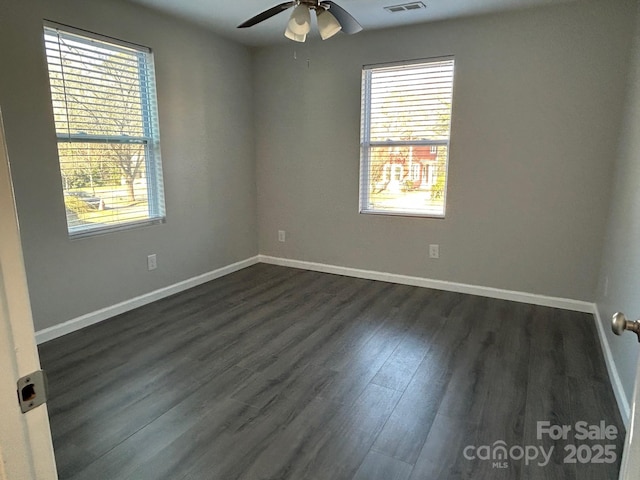 spare room featuring ceiling fan, dark wood-type flooring, and baseboards