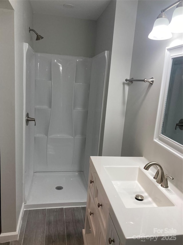 full bathroom featuring a shower, wood finished floors, and vanity