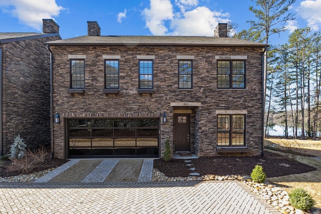 view of front of house featuring a garage, driveway, and a chimney