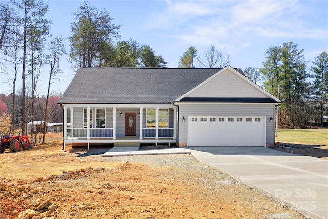 view of front facade with covered porch, roof with shingles, an attached garage, and concrete driveway