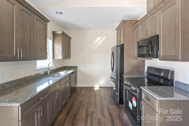 kitchen with stainless steel appliances, stone counters, a sink, and dark wood finished floors