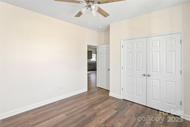 unfurnished bedroom with dark wood-style flooring, a closet, a ceiling fan, and baseboards