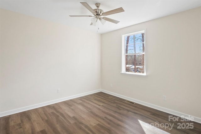 spare room featuring ceiling fan, dark wood-style flooring, visible vents, and baseboards