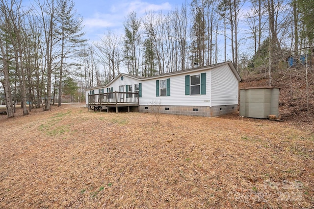 view of front of home with crawl space, a storage shed, an outdoor structure, and a wooden deck