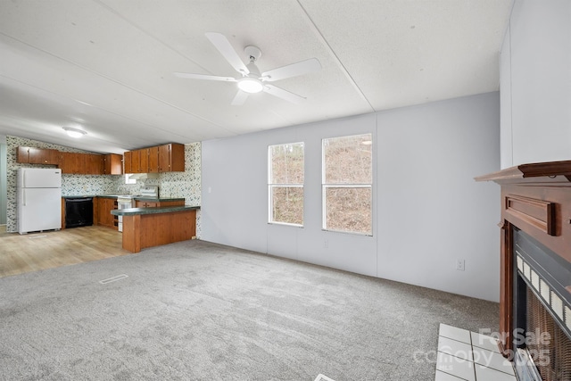 unfurnished living room featuring a fireplace with flush hearth, light carpet, and ceiling fan