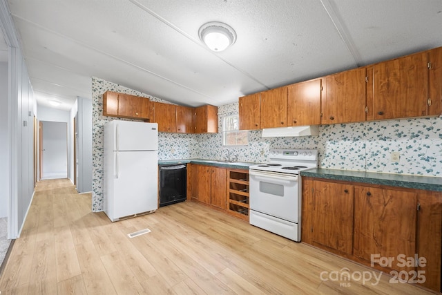 kitchen with white appliances, under cabinet range hood, and brown cabinets