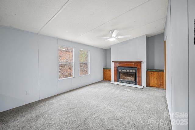 unfurnished living room featuring a fireplace with raised hearth, ceiling fan, carpet, and lofted ceiling