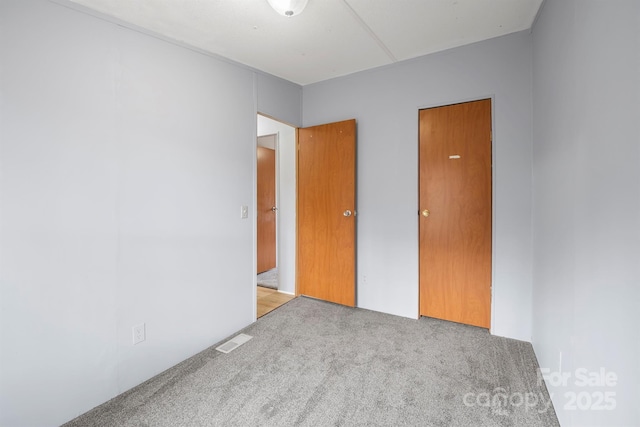 unfurnished bedroom featuring visible vents and light colored carpet