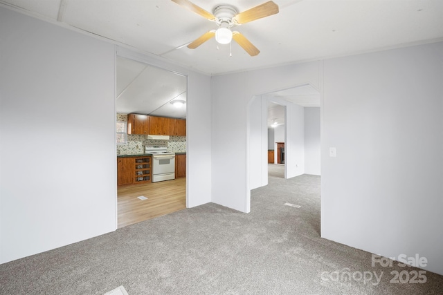 unfurnished living room with light carpet and a ceiling fan