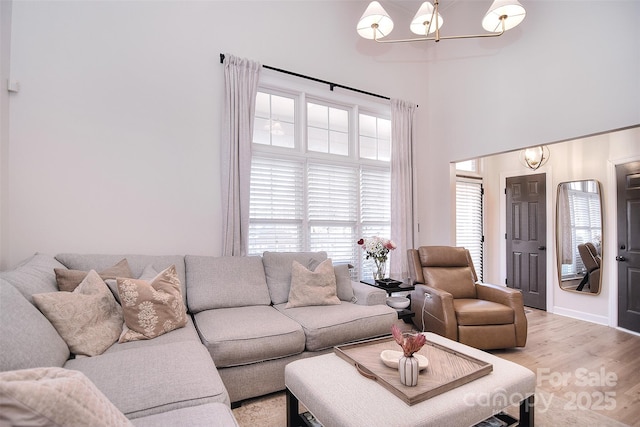 living room featuring light wood finished floors, a high ceiling, and a notable chandelier