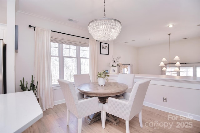 dining space with baseboards, visible vents, light wood-style flooring, ornamental molding, and a notable chandelier