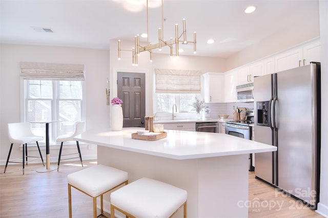 kitchen with appliances with stainless steel finishes, a breakfast bar area, a wealth of natural light, and white cabinets