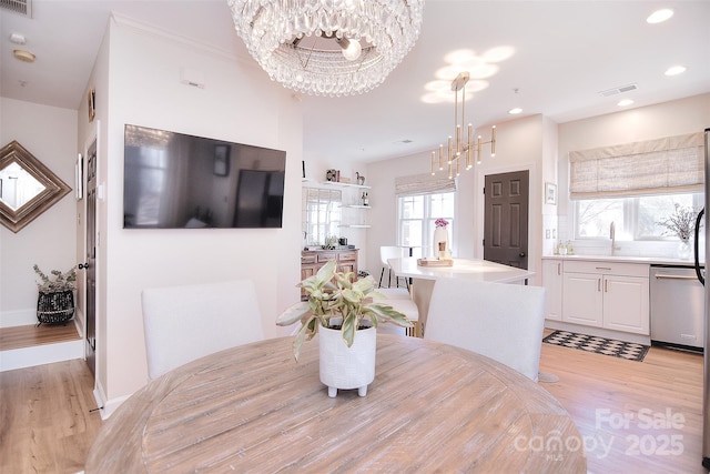 dining area with light wood finished floors, recessed lighting, visible vents, an inviting chandelier, and baseboards