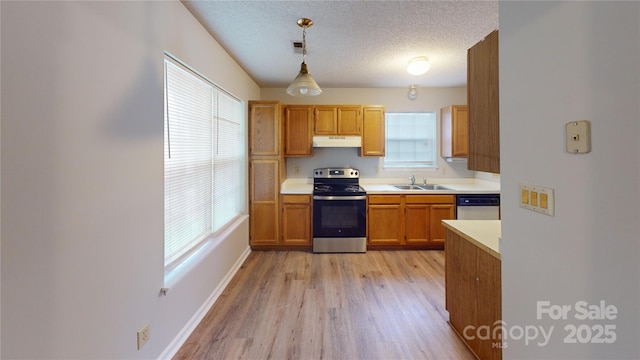 kitchen with stainless steel appliances, light countertops, hanging light fixtures, a textured ceiling, and light wood-type flooring