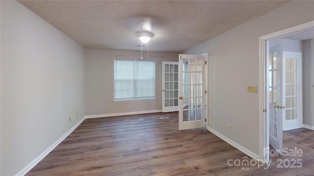 unfurnished room featuring a textured ceiling, baseboards, wood finished floors, and french doors