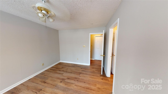 empty room featuring a textured ceiling, baseboards, and wood finished floors