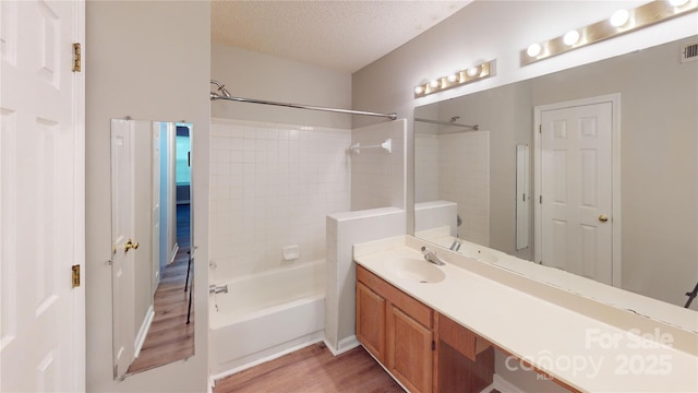 full bathroom with visible vents, shower / tub combination, wood finished floors, a textured ceiling, and vanity